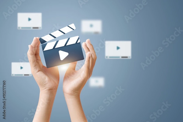 Obraz Hands holding a clapperboard with a play icon, representing video production and content creation.