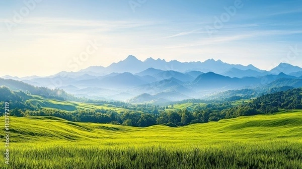 Fototapeta A stunning view of rolling green hills and majestic mountains under a clear blue sky, evoking a sense of peace and tranquility in nature.