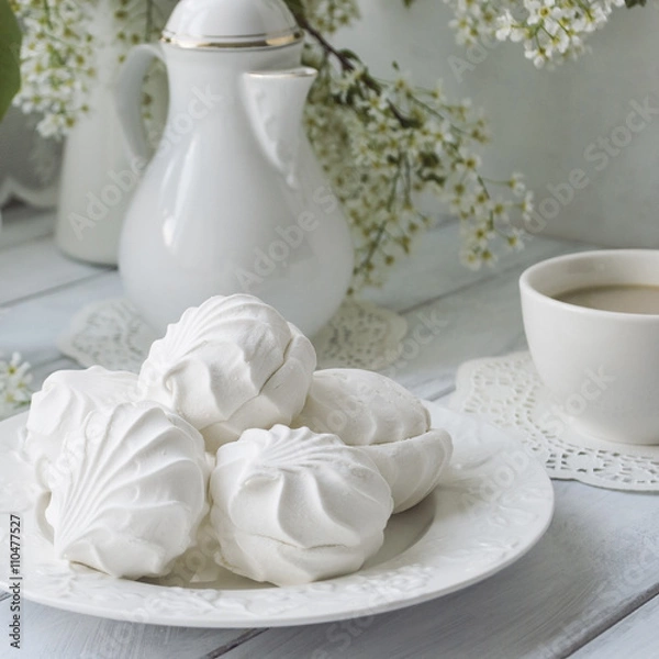 Fototapeta Russian marshmallow or zefir dessert on white plate with branches of blooming bird cherry tree, coffee pot and cup on background. Vintage. Toned.