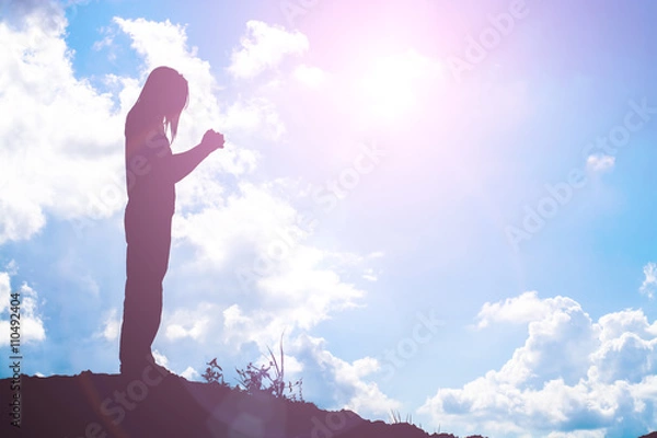 Fototapeta Silhouette of woman praying over beautiful sky background