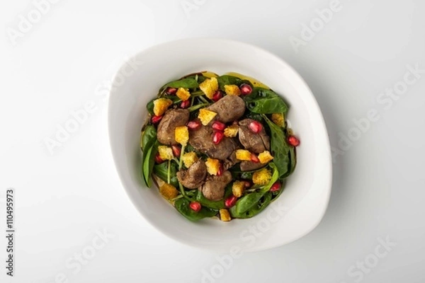 Fototapeta Salad with chicken liver, spinach, pomegranate on a white backgr