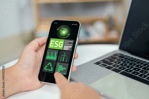 Fototapeta Hand using laptops to analyze ESG on smartphone screen in business investment strategy concept, Environment social governance investment business concept, Environmental and business growth together.