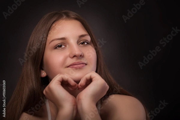Fototapeta Young girl makes a heart with her hands
