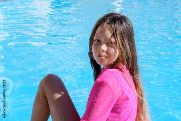 Obraz Happy teenage girl with loose, tangled hair from the wind sitting on the background of blue water, acne on the girl's forehead, selective focus