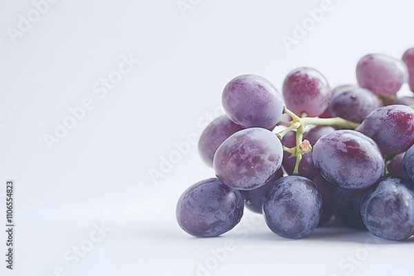 Fototapeta A bunch of red grapes rests on a white surface