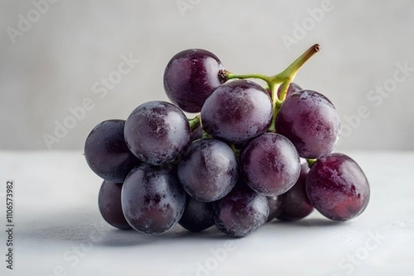 Fototapeta A cluster of plump purple grapes with a green stem