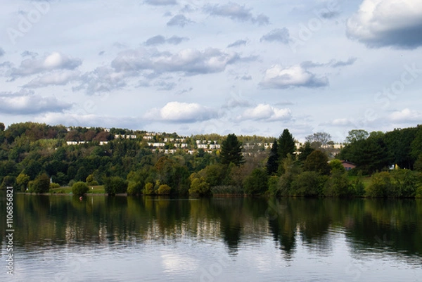 Fototapeta Lake with houses on a hill in the background on a summer day in Germany.