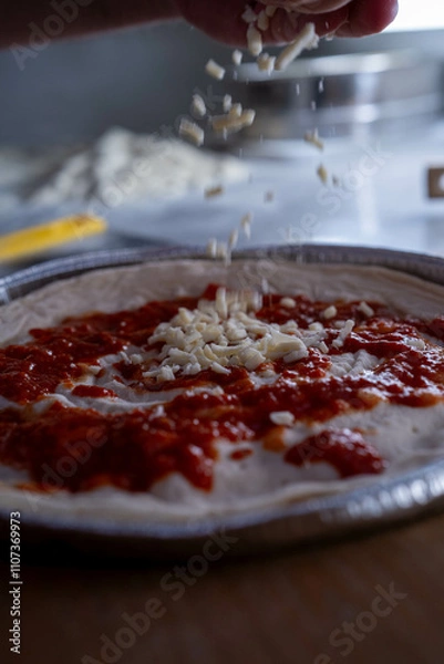Fototapeta A close-up of grated cheese being added to a pizza highlights the perfection in preparation.
