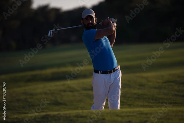 Fototapeta golfer hitting a sand bunker shot on sunset