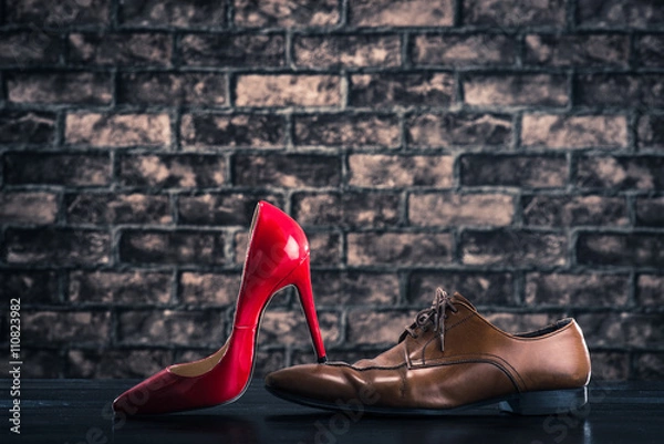 Fototapeta 赤いハイヒールに踏まれている革靴