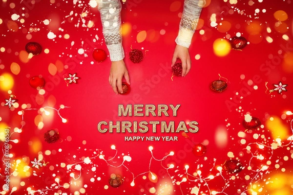 Obraz The girl is using the hand to hold the ball red decorations On a red background with christmas ornaments with led light. Top view. Christmas family traditions. Concept christmas.