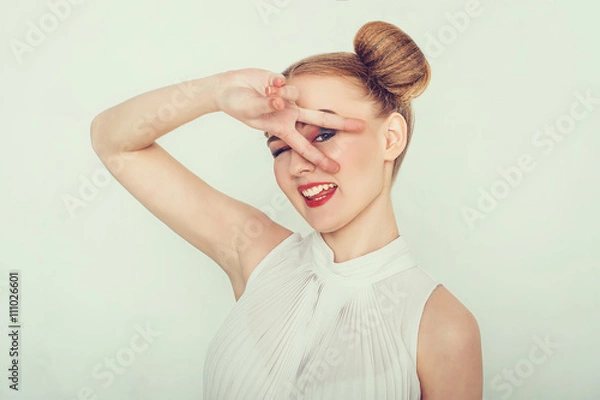 Fototapeta Beautiful girl with funny hairstyle. makes peace sign hands, smiling and showing tongue.
