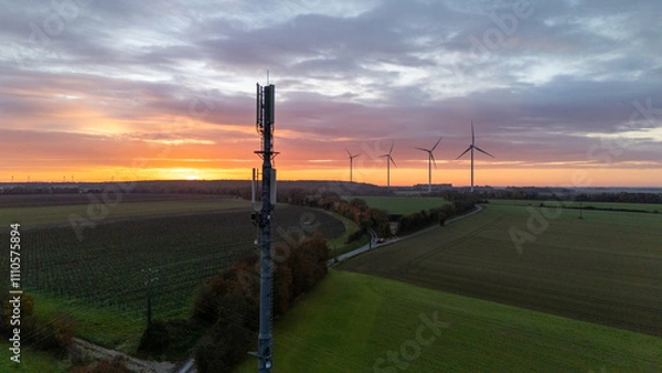 Obraz 5G Tower and Wind Turbines During Vibrant Countryside Sunset