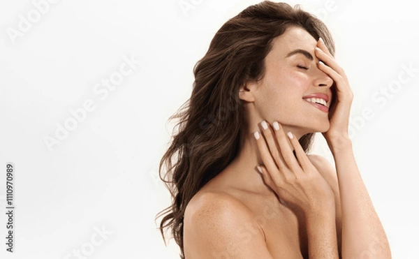 Obraz Natural Beauty Portrait of a Smiling Woman with Radian Glowing Skin and Flowing Hair, Posing with Romantic Smile against a Clean White Background. Model Touching Hydrated Flawless Skin