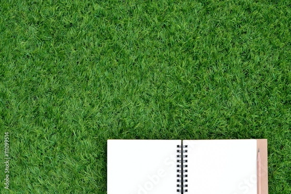 Fototapeta Blank book and pencil on the lawn with copy space for text