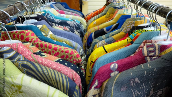Fototapeta Colorful batik shirts hanging on a rack. Close-up shot highlights intricate patterns and vibrant colors. Perfect for fashion blogs or promoting Indonesian culture