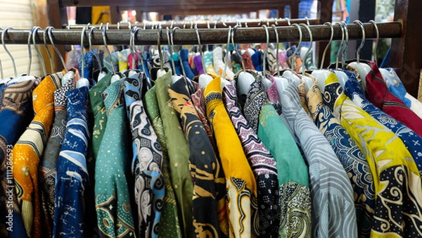 Fototapeta Colorful batik shirts hanging on a rack. Close-up shot highlights intricate patterns and vibrant colors. Perfect for fashion blogs or promoting Indonesian culture