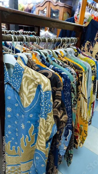 Fototapeta Colorful batik shirts hanging on a rack. Close-up shot highlights intricate patterns and vibrant colors. Perfect for fashion blogs or promoting Indonesian culture