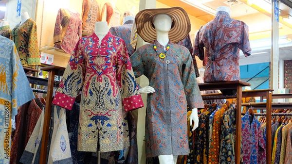 Fototapeta Colorful batik dresses displayed on mannequins in a shop. Selective focus on the dresses, shallow depth of field creates a dreamy atmosphere. Perfect for fashion blogs or promoting Indonesian culture