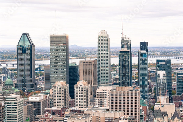 Obraz A vibrant view of Montreal’s downtown skyline with iconic skyscrapers, a backdrop of the St. Lawrence River, and a mix of modern and historic architecture.