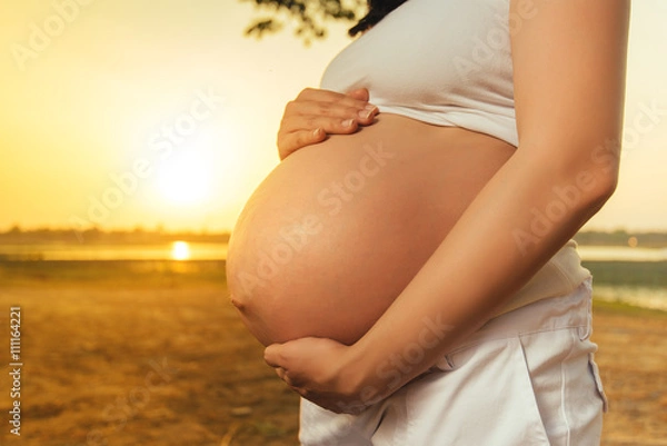 Obraz Pregnant woman relaxing lakeside sunset background