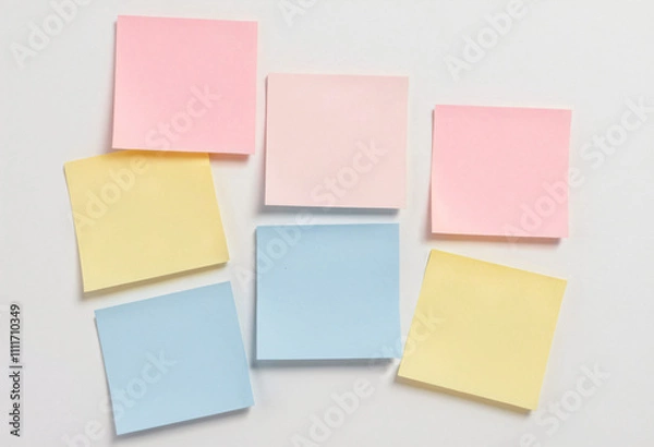 Fototapeta Image featuring three square sticky notes of different colors (e.g., pastel yellow, light blue, and soft pink) arranged neatly on a pure white background
