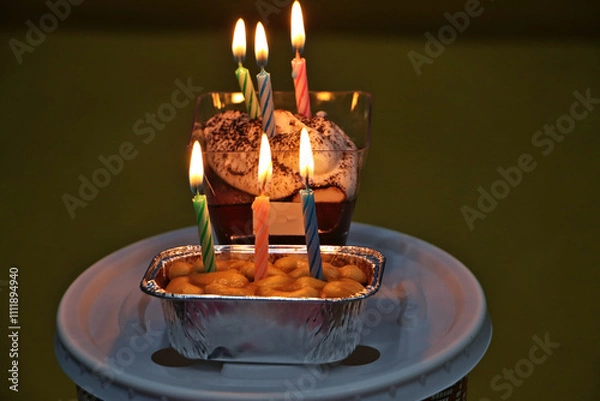 Fototapeta Candles are lit on a cake in a small square container.