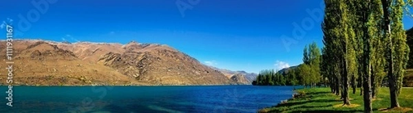 Fototapeta Serene lake with lush trees and mountains