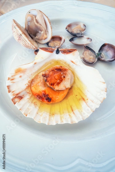 Fototapeta Delicious Mediterranean dish with Saint Jacques mussels, served on a platter in a small restaurant on the main promenade of Piran, Slovenia