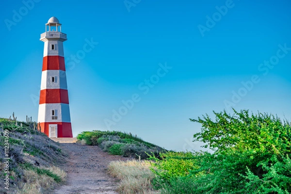 Fototapeta A lighthouse is on a hill with a clear blue sky
