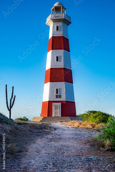 Obraz A lighthouse is on a hill with a clear blue sky