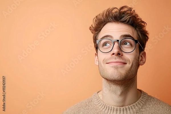 Fototapeta Smiling young man with glasses looking up, hopeful expression