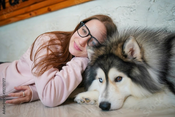 Fototapeta Girl with a husky puppy in a snowy winter setting