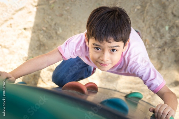 Fototapeta Little boy climbing up brave at playground
