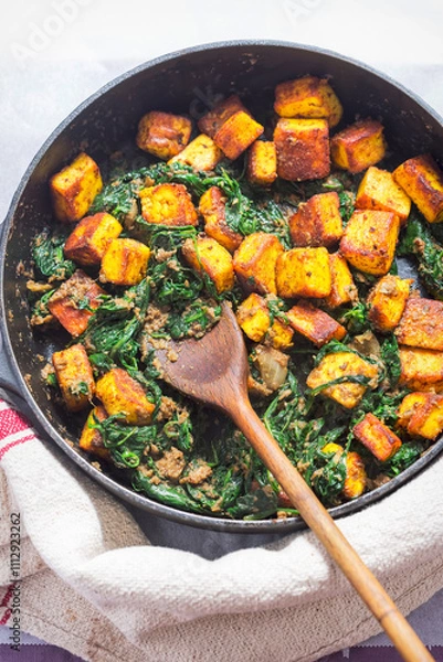 Fototapeta Saag paneer. Fried paneer cheese with turmeric, onion, garlic and spinach 