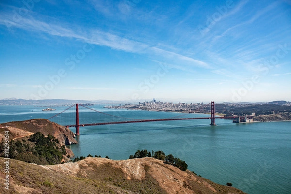 Fototapeta Golden Gate Bridge spanning San Francisco Bay, with the city skyline in the background under a clear blue sky.
