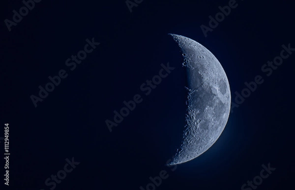 Fototapeta Half-moon glowing in the deep blue sky, creating a serene and celestial atmosphere.