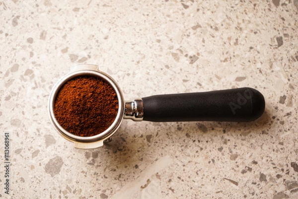 Fototapeta Freshly ground coffee in a holder for making traditional Italian espresso coffee. On a graphite table.