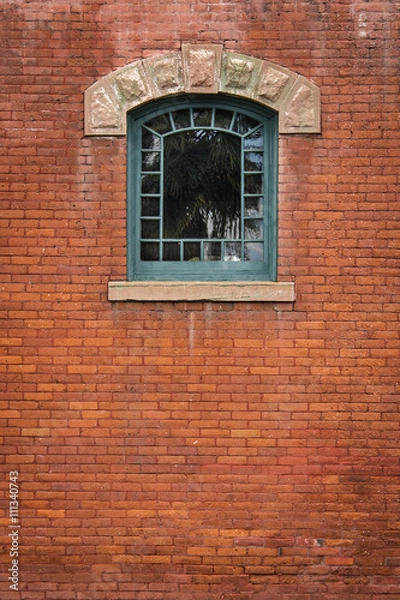 Fototapeta Arched Green Window - Center Top / Vintage Arts and Crafts arched 22-pane window set in weathered rust-colored brick wall.