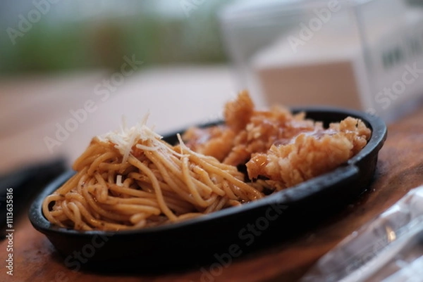 Obraz A delicious combination of crispy chicken and flavorful noodles served on a sizzling plate with vegetables