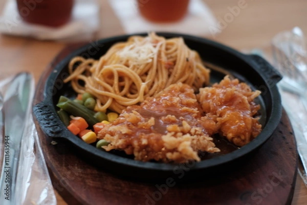 Obraz A delicious combination of crispy chicken and flavorful noodles served on a sizzling plate with vegetables
