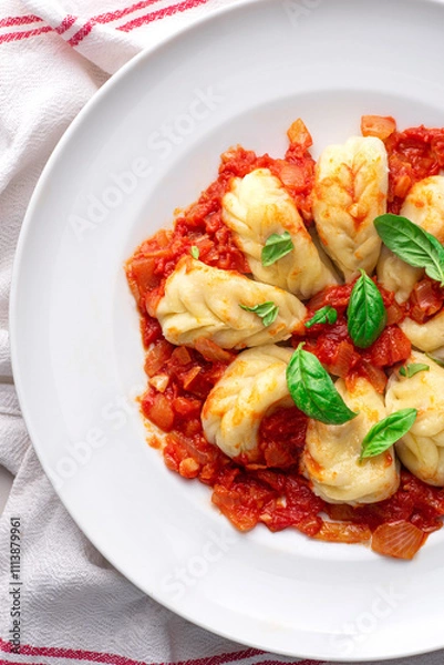 Fototapeta Culurgiones, typical ravioli of Sardinia. A first course of Sardinia: culurgiones or culugiornis, typical stuffed ravioli closed in an ear of wheat, best Sardinian culinary, pasta, tomatoes sauce