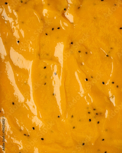 Fototapeta Passionfruit, mango jam texture with pulp in a close up on the surface. Bakery dessert concept. Full frame delicious background.