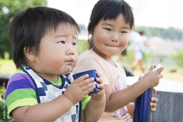 Fototapeta 公園で水筒のお茶を飲む姉弟