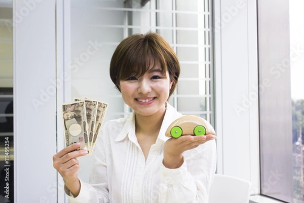 Obraz お金とおもちゃの車を持った若い女性