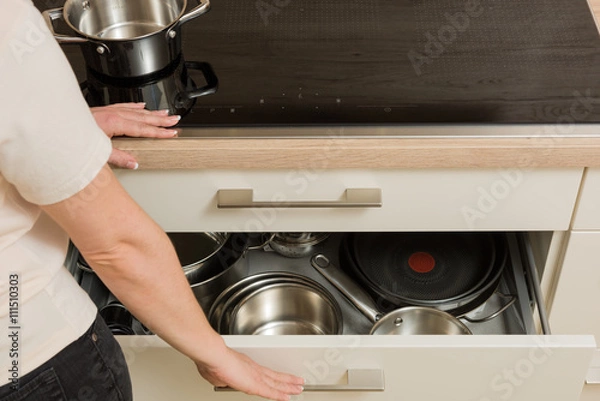 Fototapeta Woman in front of modern cooker with open drawer under the stove