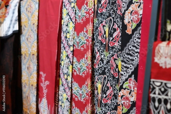 Obraz An array of Indonesian batik shirts and batik cloth hangs on the racks, displaying a variety of patterns and colors.