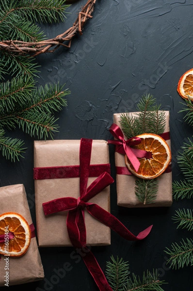 Fototapeta Christmas decoration and wrappung gifts on black background flat lay top view eco sustainable composition with pine branches and dried oranges copy space cute ribbons