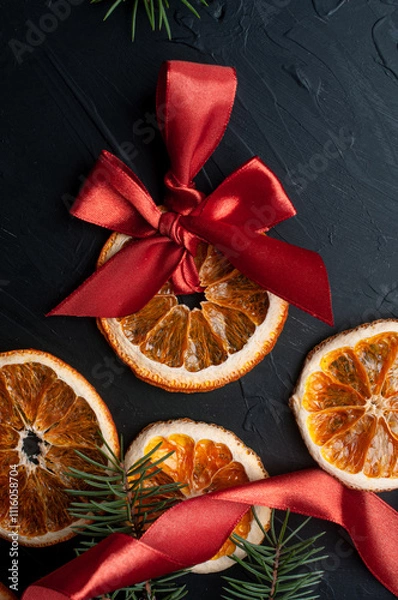 Fototapeta Christmas decoration and wrappung gifts on black background flat lay top view eco sustainable composition with pine branches and dried oranges copy space cute ribbons