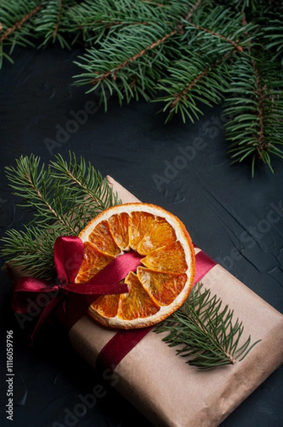 Fototapeta Christmas decoration and wrappung gifts on black background flat lay top view eco sustainable composition with pine branches and dried oranges copy space cute ribbons